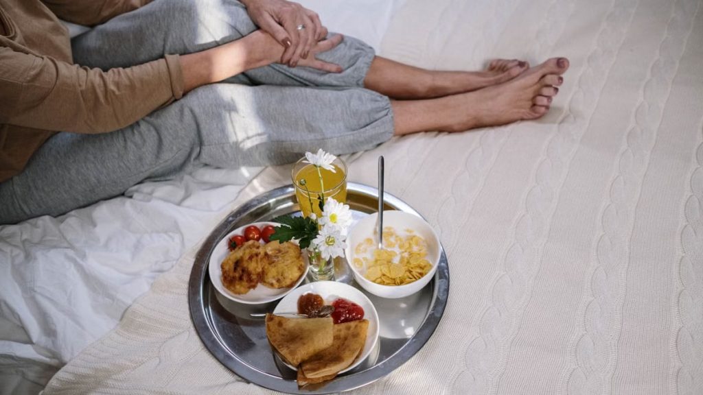 Cozy morning breakfast in bed featuring pancakes, fruit, and flowers. Perfect start to the day.