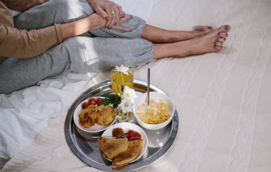 Cozy morning breakfast in bed featuring pancakes, fruit, and flowers. Perfect start to the day.